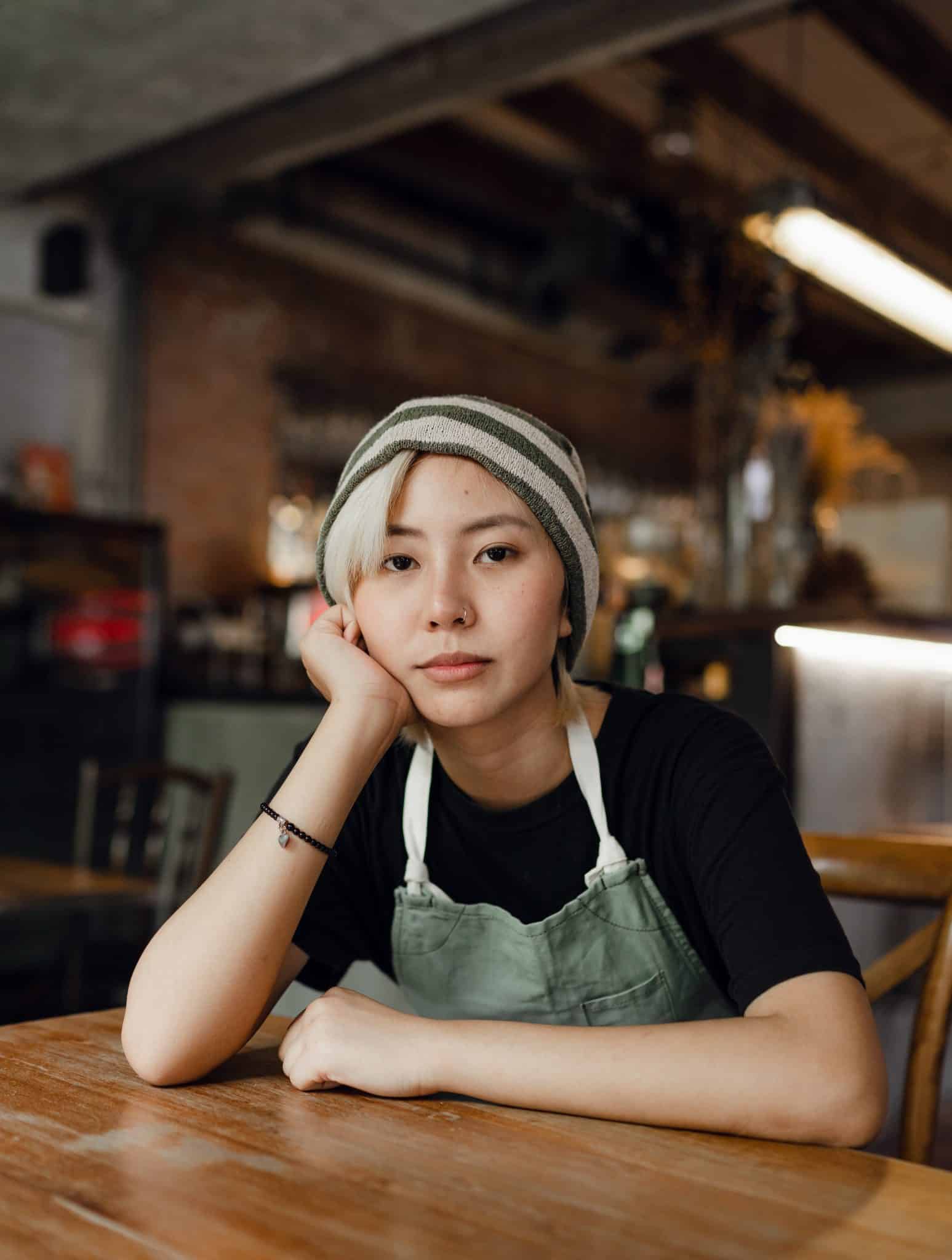 Female Barista In Beanie And Apron Resting Chin On Had 4350057 - Coach Foundation